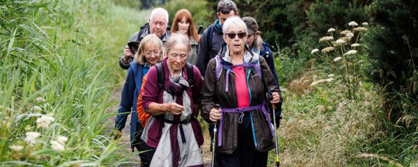 A group of Scottish Ramblers walk together through a rural footpath